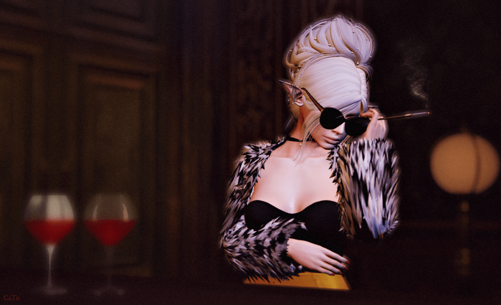 A stylish second Life female avatar with pale updo hair, dark sunglasses, and a furry jacket leans in a dimly lit bar while holding a cigarette, with two glasses of red wine blurred in the foreground, giving the scene a cool, guarded, slightly intimidating clique-leader vibe.